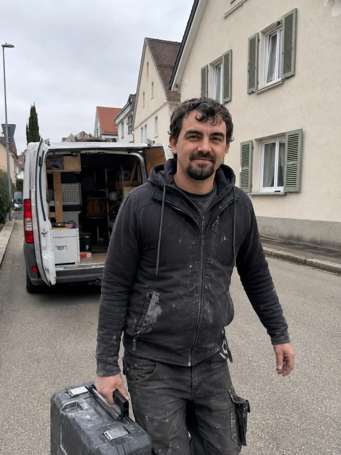 Timo Herrmann mit Werkzeugkoffer vor dem Servicefahrzeug